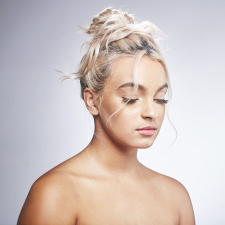 Never dull your confidence for anyone. Shot of an attractive young woman standing alone and posing against a grey background in the studio.の写真素材