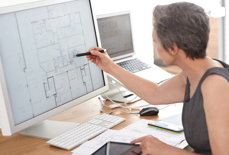 Forward-thinking architecture. A mature female architect working on building plans on her...