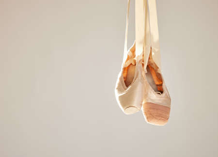 All ballet is dance, but not all dance is ballet. Shot of a pair on ballet shoes hanging in a dance studio.の写真素材