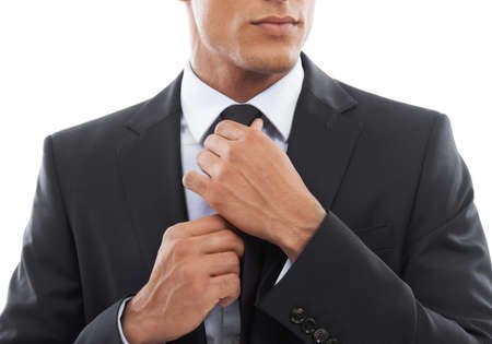 Getting ready.... Cropped image of a businessman fixing his tie against a white background.