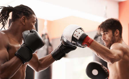 Sparring partners for now.... Shot of a young boxer practicing his punching with a partner.