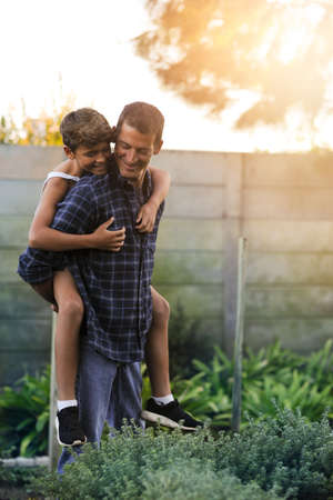 Cheerful childhood days spent with Dad. Cropped shot of a father giving his son a piggyback ride outside.の写真素材