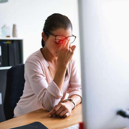 Its impossible to work with this pain. Shot of a young businesswoman suffering with a headache while working in an office.の写真素材