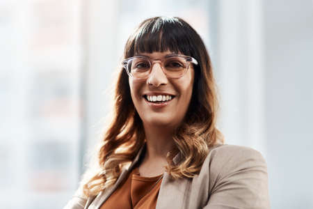 Success is a mentality you have to adapt. Portrait of an attractive young businesswoman smiling and feeling cheerful in her office.の写真素材