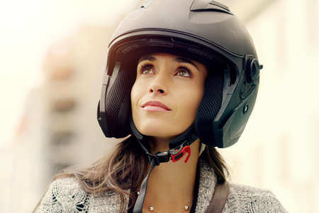 Dare to follow your dreams. Closeup shot of an attractive young woman wearing a helmet and riding her scooter through the city.の写真素材
