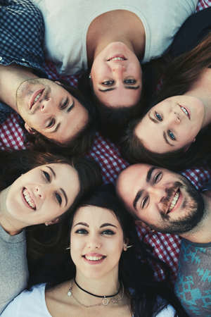 Friends for life. Portrait of a group of friends lying down with their heads together outdoors.の写真素材