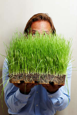 This is some good grass right here. Shot of a man obscuring his face with a patch of grass.の写真素材