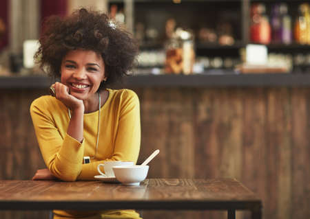 On a solo coffee date and Im loving it. Portrait of a young woman having coffee at a cafe.の写真素材