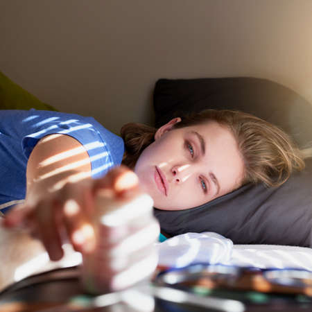 Monday morning always comes too soon. Shot of a young woman waking up and reaching for her alarm...