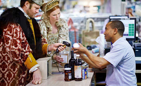 We have a coupon for that.... A king and queen buying groceries and paying at the cashier.の写真素材