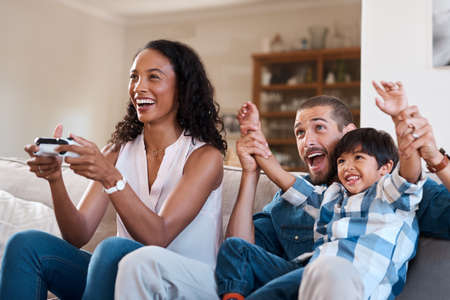 Were celebrating moms success. Shot of a woman playing video games while relaxing at home with her...
