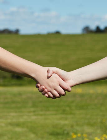 Friends till the end. Cropped shot of two unidentifiable people holding hands while standing in a grassy field.の写真素材