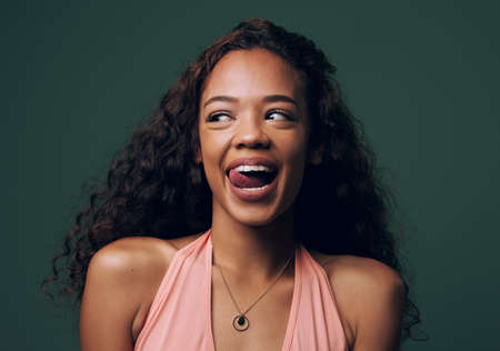 Fun is her middle name. Cropped shot of an attractive and quirky young woman posing against a green background in studio.の写真素材