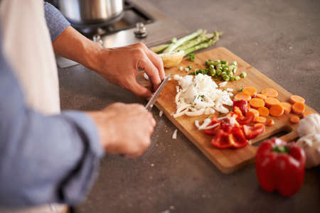 Variety is the spice of life. Cropped shot of a man chopping vegetables on a countertop.の写真素材
