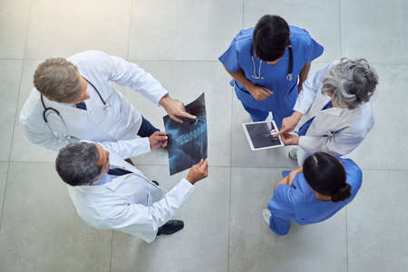 Working together to uphold their quality standard of healthcare. High angle shot of a group of medical practitioners working together in a hospital.の写真素材