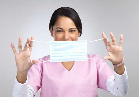 Let me help you. Cropped portrait of an attractive young female healthcare worker holding up a mask...