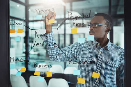 His strategies are bulletproof. Cropped shot of a handsome young businessman working on a glass wipe...