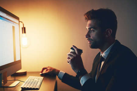 Coffee is key to getting through those long nights. Cropped shot of a young businessman drinking...