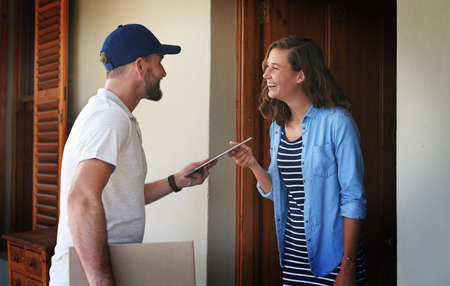 I cant believe youre here so soon. Shot of a young woman using a digital tablet to sign for her...