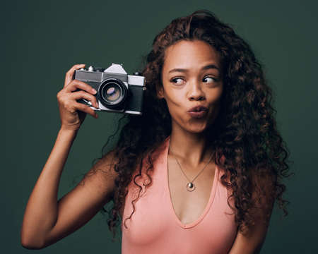 Having fun with photography. Cropped shot of an attractive and quirky young woman posing against a green background in studio.の写真素材