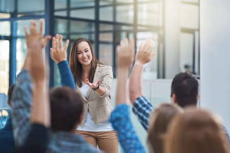 The audience has the answer. Shot of a group of people raising their hands in a seminar.の写真素材