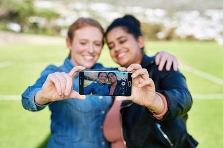 We have to capture our friendship together. Shot of female friends taking a picture together outside.の写真素材