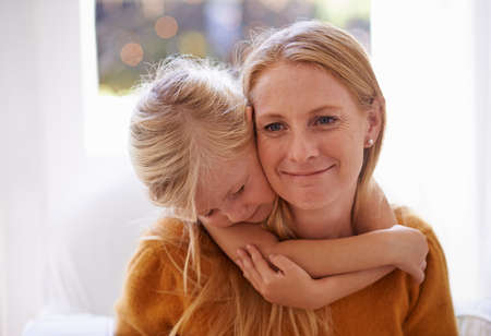 The joys of motherhood. Cropped shot of a little girl hugging her mother from behind.の写真素材