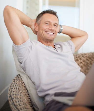 Relaxing is the healthiest choice he made. A mature man leaning back on a chair with his hands behind his head.の写真素材
