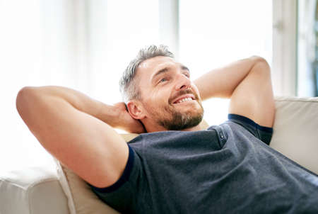 Enjoying his day off. Shot of a handsome mature man relaxing on the sofa at home.の写真素材