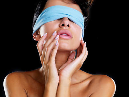 Discover your beauty. A head and shoulders shot of a beautiful model wearing a blue blindfold and holding her hands up to her cheeks.の写真素材
