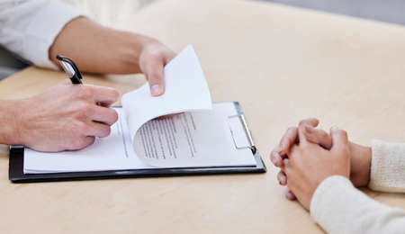 Im officially part of the team. Cropped shot of two unrecognizable businesspeople sitting together in the office and signing a contract.の写真素材