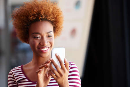 Connected to modern life. A young businesswoman using her phone in the office.の写真素材