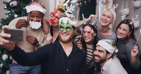 Crazy friends make fun memories. Shot of a group of young friends wearing funny hats and taking...
