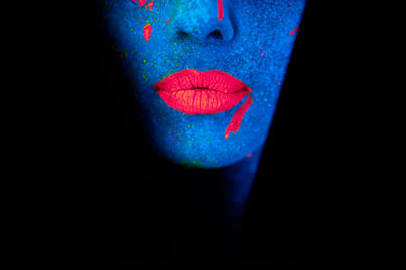 Luminous lips. Shot of a young woman posing with neon paint on her face.の写真素材
