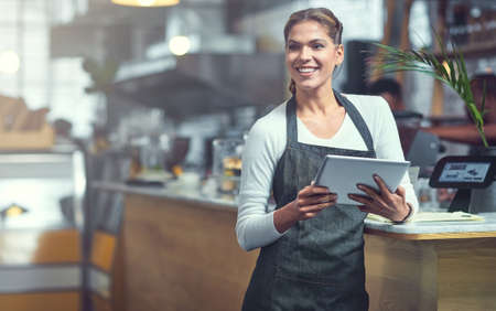 Every entrepreneur needs to be using this app. Shot of a young woman using a digital tablet in the store that she works at.の写真素材