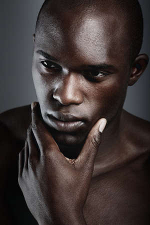 Hes the silent thinking type. An african male looking thoughtful in studio.の写真素材