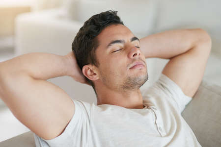 Ahhhweekend. Shot of a young man relaxing on the sofa at home.の写真素材