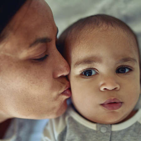 Mothers love their kids instinctively. Shot of a mother kissing her adorable baby boy on the cheek...
