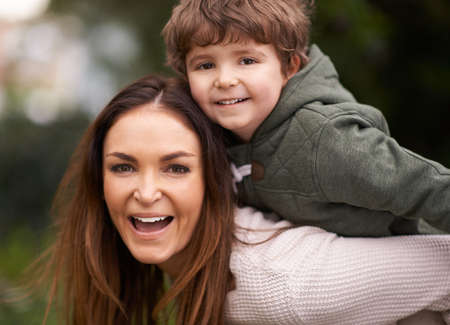 She treasures her only son. Shot of a beautiful mother giving her son a piggyback ride outdoors.