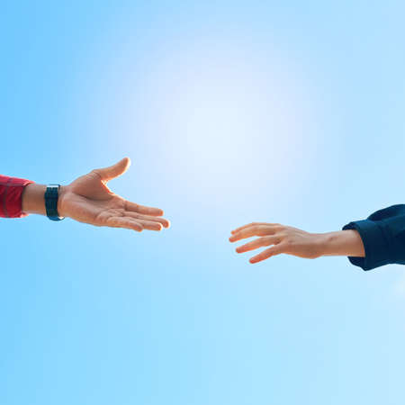 Theres always a helping hand to be found. Shot of two unidentifiable hikers reaching for each others hands against a clear blue sky.の写真素材