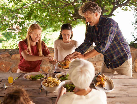 Lets eat. A view of a family preparing to eat lunch together outdoors.