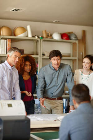 We should strike while the irons hot. Shot of a group of architects having a meeting in their...