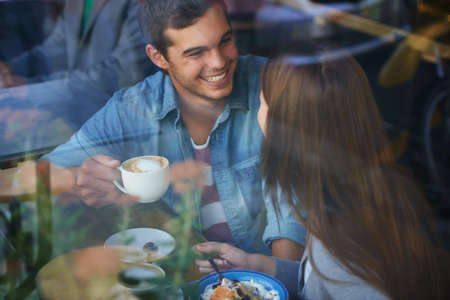 Cafe dating. Shot of a young couple drinking coffee and talking in a cafe.
