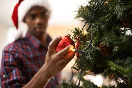Christmas is my favourite time of year. Shot of a handsome young man decorating a christmas tree.の写真素材