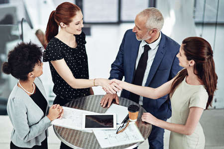 An alliance built on trust. Shot of two businesswomen shaking hands during a team meeting at work.の写真素材