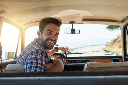 Comfortable back there. Rearview portrait of a handsome man enjoying a summer roadtrip.の写真素材