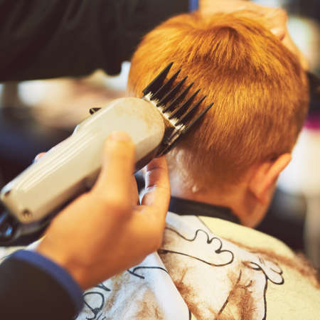 Time for a new look. Closeup shot of a young boy getting a haircut at a barber shop.の写真素材