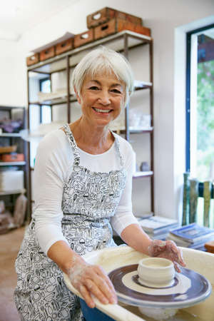 I just love working with my hands. Shot of a senior woman making a ceramic pot in a workshop.の写真素材