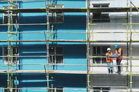 Watch the experts in action. Shot of a young man and woman going over building plans at a construction site.の写真素材