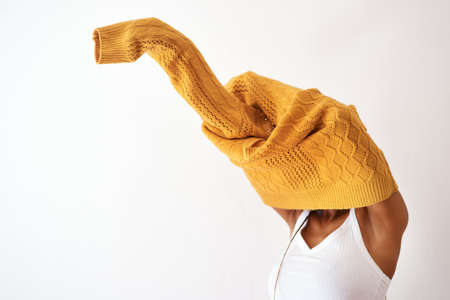 Its knitwear season. Studio shot of an unrecognizable woman getting dressed against a white...